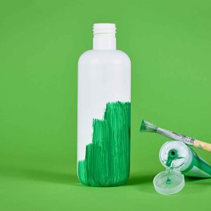 Greenwashing concept with white plastic bottle being painted green